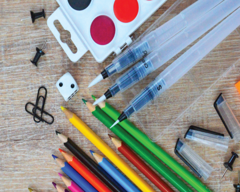 Art supplies on a desk: paints, paperclips, colored pencils and dice