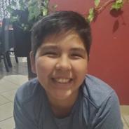 An 11-year-old boy looks at the camera with a big smile. He has short dark hair and is wearing a blue t-shirt.